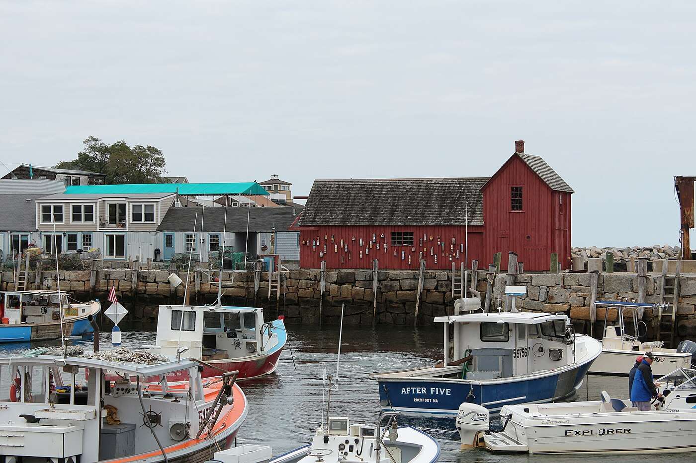 Motif No. 1, the red fishing shack hung with buoys on Rockport's Bradley Wharf, with lobster boats in the harbor